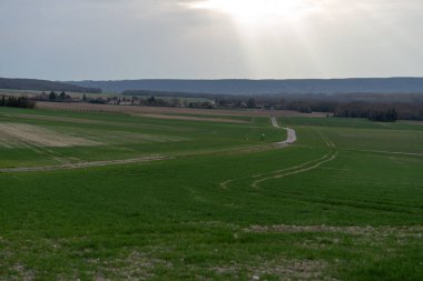La Roche-Guyon 'daki yumuşak yeşil tarlalar kıvrımlı yollar ve uzak bir köy ile benekli haldeyken alacakaranlık yumuşak bir ışık karada sakinleştirici bir parıltı yayıyor..