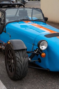 Çarpıcı turuncu çizgili mavi bir araba La Roche-Guyon 'da büyüleyici bir caddede park halinde. Resimli arkaplan zengin tarihi vurguluyor.