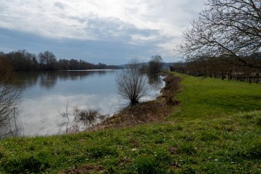 La Roche-Guyon 'da huzurlu bir manzara gözler önüne seriliyor. Seine Nehri' nin yumuşak suları yemyeşil ve uzak ağaçların çerçevelediği bulutlu bir günün ışığını yansıtıyor..