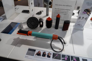 Chambourcy, France-09.03.2025 Çağdaş bir sergi salonunda belirgin bir şekilde çeşitli saç şekillendirme araçları, parlak tasarımlar ve canlı renkler sergilenmektedir.