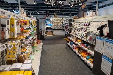 Chambourcy, France-09.03.2025 parlak ışıklı koridorlar, renkli ambalajlı ve yenilikçi ürünlerle cazip müşterileri hareketli bir perakende satış alanında bir dizi teknolojik cihaz ve aksesuar sergiliyor..