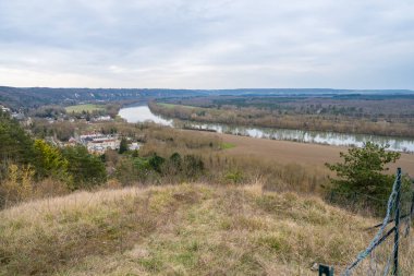 Visitors admire the tranquil view from the heights of La Roche-Guyon, where the Seine River gracefully winds through lush, green valleys. clipart