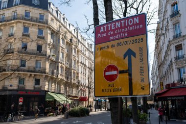 Parlak bir trafik levhası, güneşli bir günde Paris 'in işlek bir semtindeki büyüleyici kafelerin ve ağaçların arasında sokak yönlerinin değiştiğini bildiriyor..