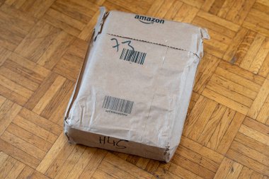 İyi giyimli kahverengi bir paket, seyahat işaretleri taşıyan ahşap bir zeminde duruyor. İçeriği bir gizem olarak kaldı. Havada heyecan ve beklenti uyandırdı..