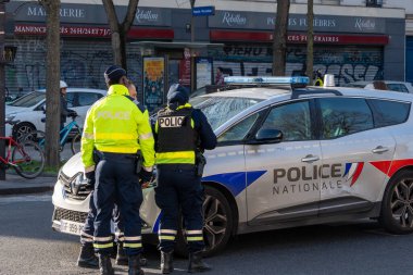 Memurlar, hareketli bir şehir caddesinde devriye arabalarıyla sohbet ediyor ve hareketli bir öğleden sonra toplum güvenliğine olan bağlılıklarını sergiliyorlar..