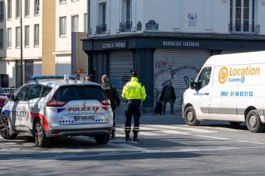 Memurlar Paris kavşağında düzeni sağlayıp trafiği yönlendirirken bir kargo aracı da öğleden sonra güneşli havalarda yakınlardaki iş yerlerinin önünden geçiyor..