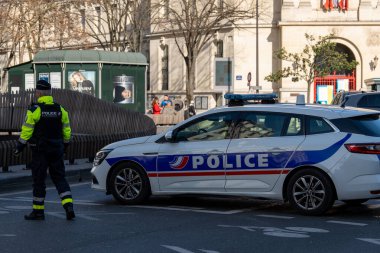 Polis memurları hareketli bir şehir bölgesinde tetikte bekliyor, yayalar aydınlık bir günde yürürken güvenliği teşvik ediyorlar..