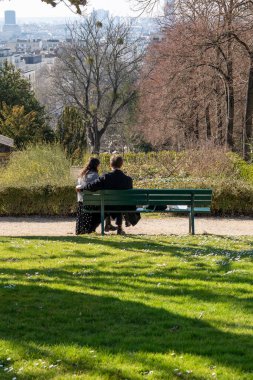 Paris, Fransa-02-03-2025 Pere Lachaise 'de sakin bir park ortamında bir çift, tomurcuklanan ağaçlar, yeşil çimenler ve gelişmekte olan bir manzara arasında mahrem anları paylaşıyor..