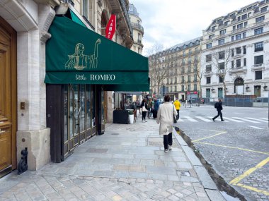 Paris, Fransa-26-02-2025 Çiftler ve bireyler klasik Paris mimarisi ile çevrili tuhaf bir butiğin önünden geçerken bahar havası hareketli sokakları hayat ile dolduruyor..