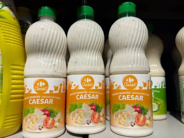 Paris, Fransa-02-03-2025 Üç şişe Sezar sosu bir süpermarket rafında, kremalı dokularını ve iştah açıcı etiketlerini sergiliyorlar,.