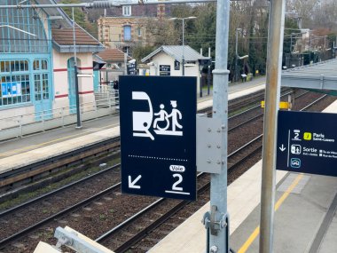 Paris, Fransa-28-02-2025 Yolcular için Platform 2 'yi gösteren açık bir yön işareti. Mekan, tuhaf binalar ve yemyeşil alanlarla çevrili sessiz bir tren istasyonu..