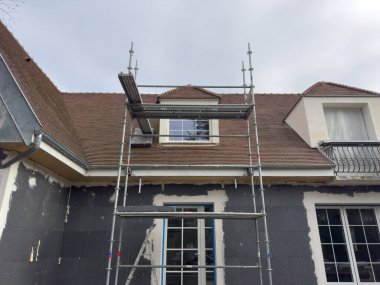 İşçiler tarihi bir evi yenilemekle meşguller, üst kata ulaşmak için iskeleyi kullanıyorlar. Çatı güncelleniyor, özelliğe karakter ve cazibe ekleniyor.