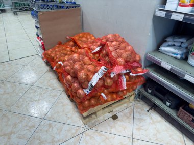 Ağların içindeki renkli soğan demetleri kalabalık bir markette davetkar bir gösteri yaratıyor. Mutfağı için hazır taze ürünleri olan müşterileri cezbediyor..