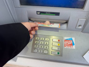 Paris, Fransa-04.03.2025 El bankamatiğe para toplamak için uzandı. Bu durum, finansmanlarını canlı bir şehir ortamında yöneten bireylerin günlük rutinini yansıtıyor..