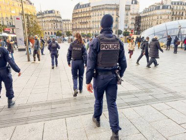 Paris, Fransa-04.03.2025 Bir grup polis memuru güvenli bir şehir meydanında yürüyor. Kalabalık kıtır kıtır öğleden sonranın keyfini çıkarırken onların varlığı güven hissi veriyor..
