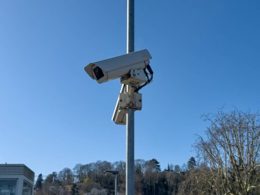 Villennes-sur-Seine, Fransa-06-03-2025 gözetleme kameraları bir direğe monte edilmiş, hareketli şehir ortamını gözlüyor, güneş ışıl ışıl bir şehir zeminini aydınlatıyor.