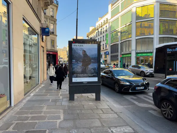 Paris, Fransa-05-03-2025 Şık bir semtteki canlı bir şehir caddesinde yayalar yol boyunca yürürken moda reklamları sergileniyor.