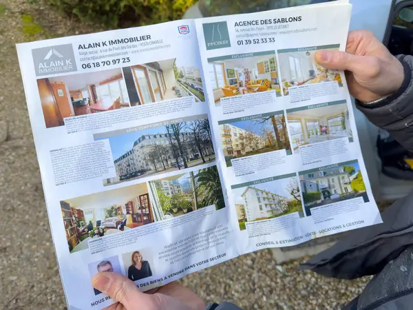 Villennes-sur-Seine, Fransa-05-03-2025 Bir kişi çeşitli gayrimenkul fırsatlarını gösteren bir broşür tutuyor..