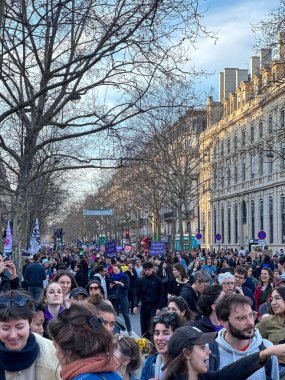 Paris, Fransa-08-03-2025 Sesler canlı bir gösteride birleşiyor. İnsanlar şehirde yürüyorlar. Parlak bir öğleden sonra sosyal değişimi destekliyorlar..
