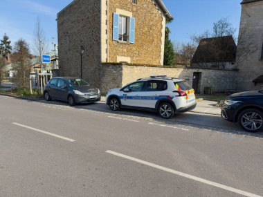 Villennes-sur-Seine, Fransa-08-03-2025 Bir polis arabası sakin bir yol boyunca eski bir evin yanında duruyor, güneşli bir öğleden sonra güneşli bir günde güneşleniyor,.