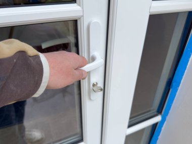 Bir el parlak bir kapı koluna uzanır, yeni yenilenmiş bir alana girmeye hazırlanır, ışık dolu, taze renkler ve dokular sergilenir..