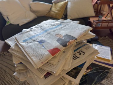 Villennes-sur-Seine, France-12-03-2025 Üst üste yığılmış, eski gazeteler hoş geldin oturma odasında oturur, eski haber parçalarını yakalar yumuşak yastıklar ise ortama sıcaklık katar..