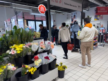 Paris, Fransa-16-03-2025 Müşteriler hareketli bir çiçek sergisine göz gezdirirken diğerleri kasada sıra beklerken, gri bir kış gününe sıcaklık getiriyorlar..