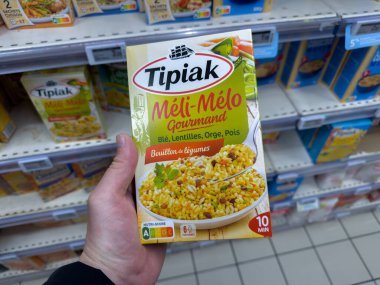 Paris, Fransa-16-03-2025 Bir el, çeşitli yemek seçenekleriyle dolu bir marketin koridorunda durup, bir anlık bir mutfak keşfi portresi çizerken Melange Gourmand 'ın renkli bir kutusunu tutuyor..