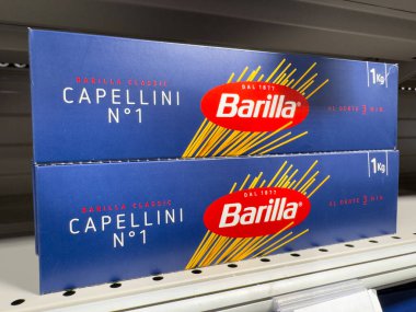 Villennes-sur-Seine, Fransa-01.03.2025 capellini makarna kutuları floresan ışıklarının altındaki bir süpermarket rafında güzelce dinleniyor ve müşterileri aşçılık potansiyellerini keşfetmeye teşvik ediyor. Hayat dolu.
