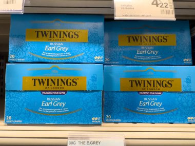 Villennes-sur-Seine, Fransa-01.03.2025 Earl Grey çay kutularının canlı bir görüntüsü süpermarket raflarını doldurur ve parlak bir mağaza arka planında mavi ambalajı gösterir. Müşteriler yakınlarda geziniyor.