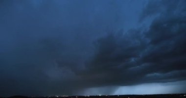Şiddetli bir sağanak yağış ve yıldırımların görünür perdesiyle fırtına bulutu yavaşça kameraya yaklaştıkça ve daha yoğun bir şekilde yanıp sönerken,