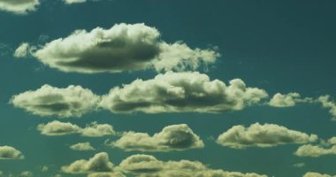 Güzel pofuduk bulutların zamanı açık mavi gökyüzünde değişiyor ve hareket ediyor.