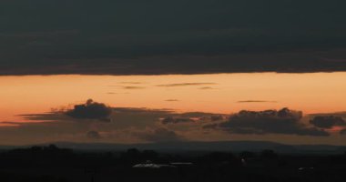 Ufukta dalgalanan kara bulutların yakın çekim zamanı. Gün batımı gökyüzünün ışıldayan turuncu şeridi.