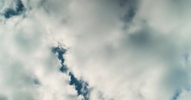 Büyük beyaz kabarık bulutlar arasında beliren mavi lekeler ile neredeyse bulutlu gökyüzü zamanı. Dönen, değişen ve duman ve dalgaları hatırlatan desenler yaratan.