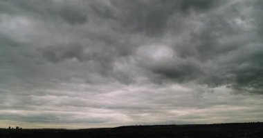Geniş açılı zaman dilimi. Etkileyici gri bulutlu gökyüzü. Kameraya doğru hareket eden bulutlar ve alçak karanlık ufuk.