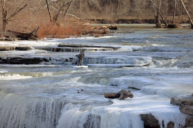 Akıntılar ve şelale kışın küçük bir nehirde çağlıyor.