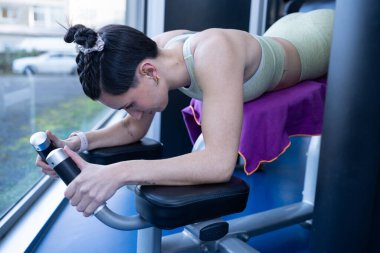 Concentrated sportswoman strengthening back muscles using hyperextension machine in modern fitness center, promoting healthy lifestyle and physical wellbeing clipart