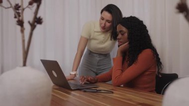 Dizüstü bilgisayarda işbirliği yapan genç iş kadınları, çağdaş ofis ortamında proje tartışmasına girişmek, profesyonel takım çalışmasını ve yenilikçi problem çözme yaklaşımını sergilemek