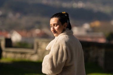 Beyaz bir kürk giyen turist Combarro 'nun büyüleyici caddelerinde yürüyor, Galiçya, İspanya' da pitoresk bir sahil kasabası, güneşli havanın ve güzel manzaranın tadını çıkarıyor.