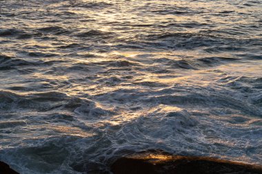 Altın gün batımı dalgalı bir denizin yüzeyine yansıyor köpükle Punta Faxilda 'da, Bari Sardo kasabası yakınlarında, Ogliastra, Sardunya, İtalya