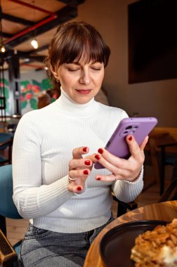 Kafede otururken telefonla konuşan gülümseyen kadın portresi, öğle yemeği molası.