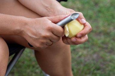 Women's hands peel potatoes with a knife, close-up clipart