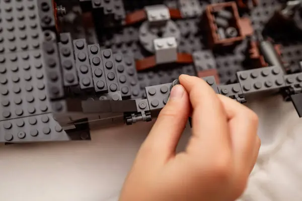 Çocukların elleri inşaat setinin küçük parçalarını topluyor, yakın plan.