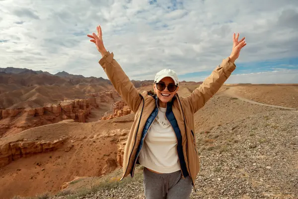 Turist ellerini kaldırdı ve güzel turuncu dağ kanyonlarına gülümsedi.