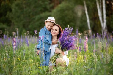 Lupin çiçekleriyle dolu bir tarlada anne ve oğul. Yaz aile kavramı.