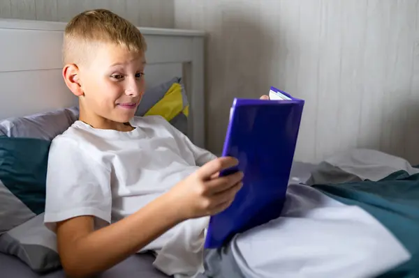 Sarışın genç çocuk yatmadan önce kitap okuyor.