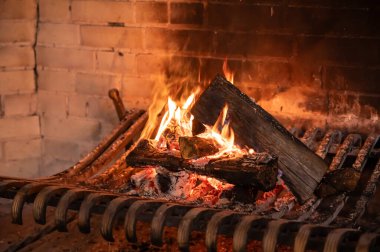 a large old brick fireplace with metal grates and a fire burning in it clipart