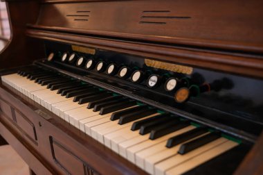 Ahşap detaylar ve karmaşık anahtarlarla eski müzik aletlerinin cazibesini yakalayan antik bir harmonyumun yakın çekimi..