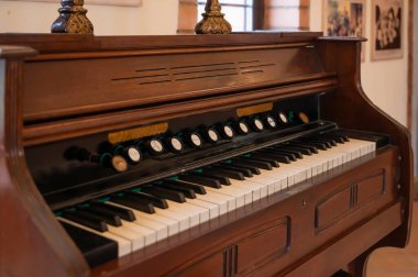 Ahşap detaylar ve karmaşık anahtarlarla eski müzik aletlerinin cazibesini yakalayan antik bir harmonyumun yakın çekimi..