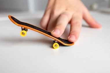 Beyaz arka planda sarı tekerlekleri olan oyuncak parmaklarla oynayan çocukların elleri, seçici odaklanma